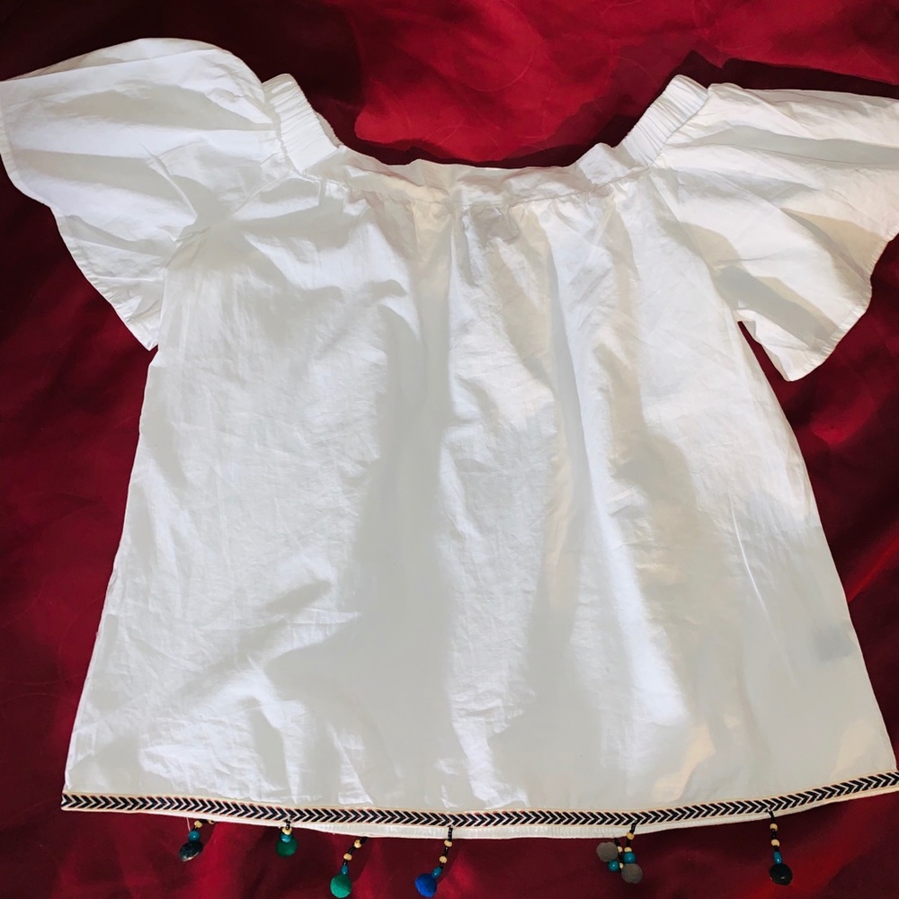 Off-shoulder top with pom poms and chevron edge.
